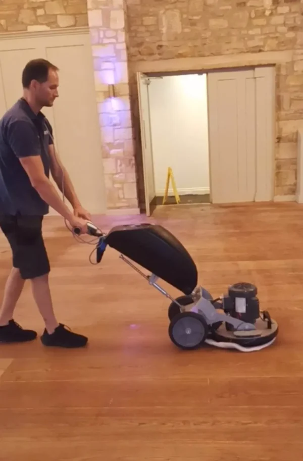 wood-floor-machine-cleaning-venue Cleaning an oak floor with a rotary machine and soft pad in a stone-walled venue